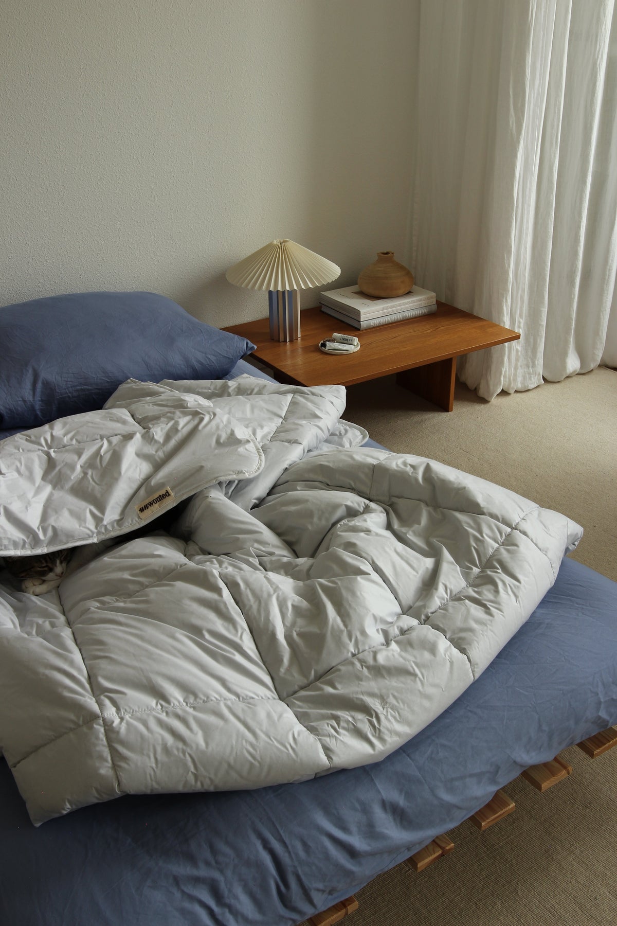 UNWONTED alpaca duvet on an unmade bed next to a bedside lamp